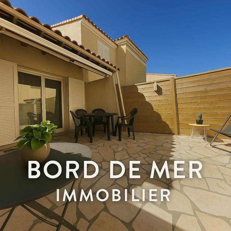 un patio avec une table et des chaises devant une maison dans l'établissement Marine Escape, à Aresquies