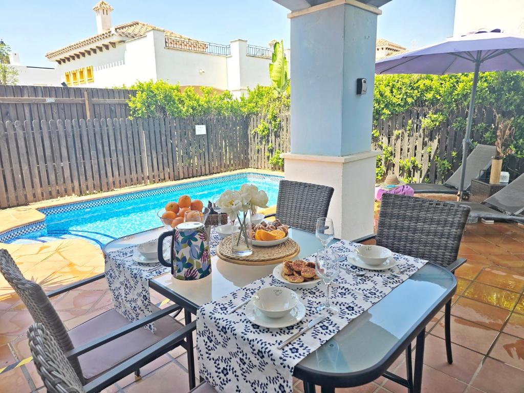 a table with a bowl of fruit on it next to a pool at Villa Azul Mar Menor by Rentalole in Las Casicas