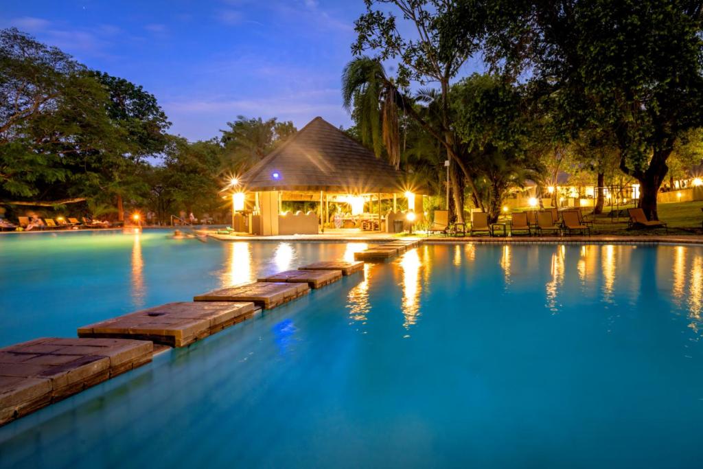 une piscine la nuit avec un bâtiment en arrière-plan dans l'établissement Sanbonani Resort Chalets, à Hazyview