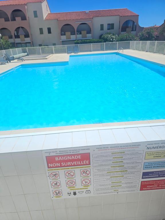 - une piscine dans un complexe avec un panneau dans l'établissement Le Patio 6 Personnes Piscine Barcarès village, au Barcarès