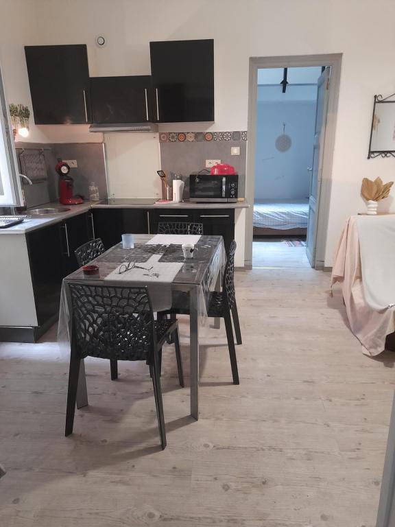 une cuisine avec une table et des chaises dans une pièce dans l'établissement Escale Voltaire T2 au calme, CV, WIFI, à Narbonne