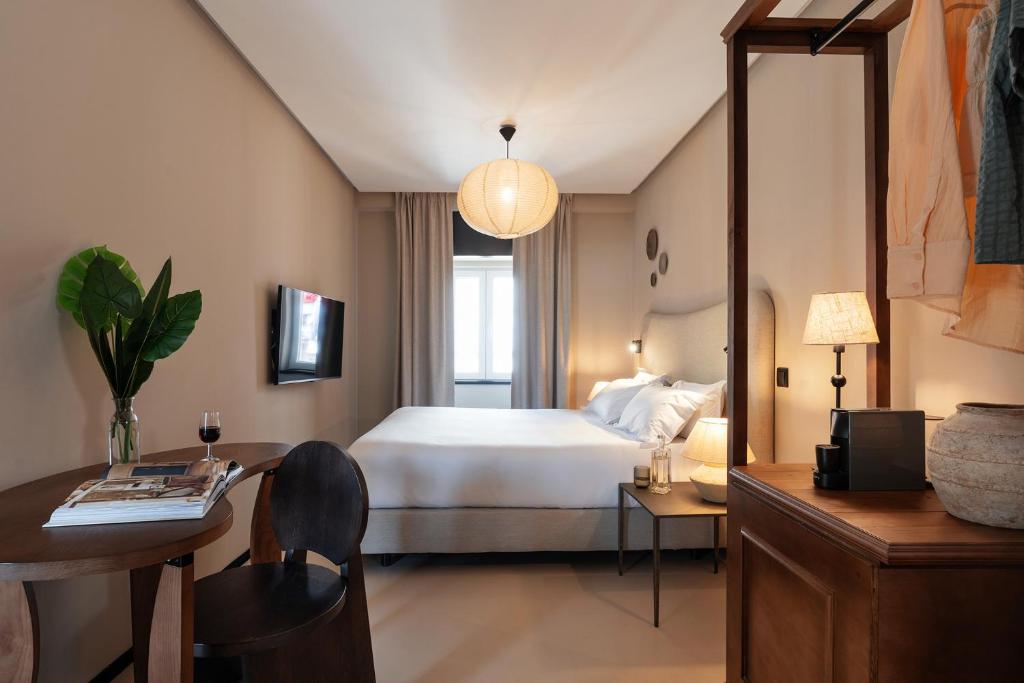 a hotel room with a bed and a table and a desk at Casa Teva Lisboa Boutique Hotel by chic&basic in Lisbon