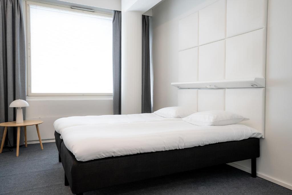 a bedroom with a large bed and a window at Omena Hotel Joensuu in Joensuu