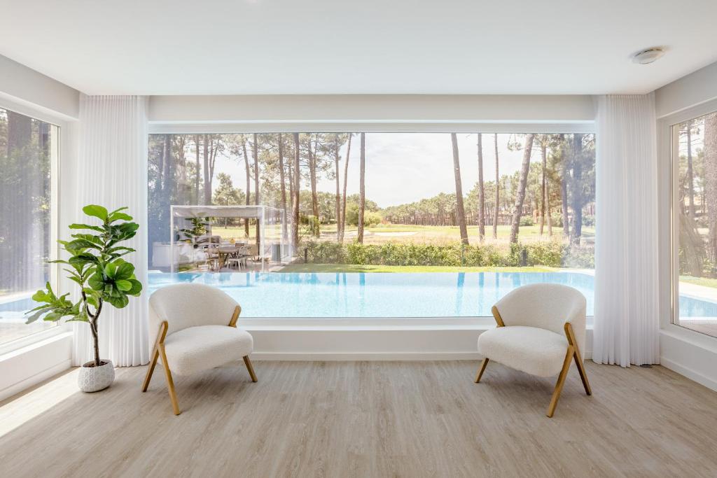 un soggiorno con 2 sedie e una piscina di Aroeira Modern Grand Villa With Pool by Homing a Aroeira