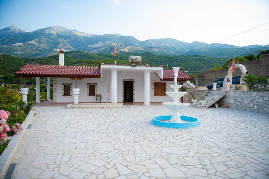 uma casa com uma fonte na frente com montanhas em Vila Beleri 