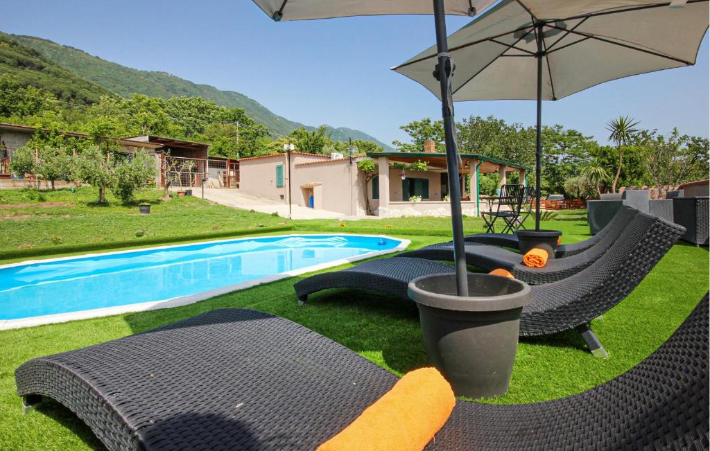 a pool with chairs and an umbrella in the grass at Lovely Home In Avella in Avella