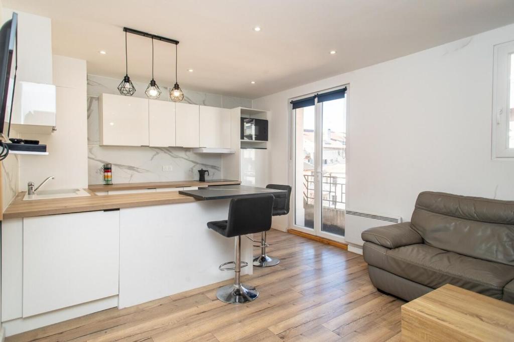 a kitchen and living room with white cabinets and a couch at Le Meublé du centre in Thonon-les-Bains