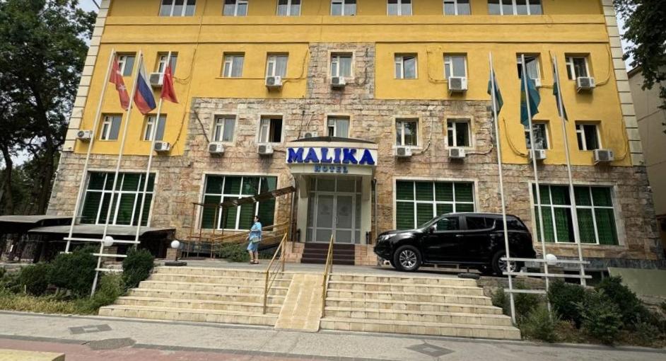 a car parked in front of a building with flags at Hotel Malika Tashkent in Tashkent