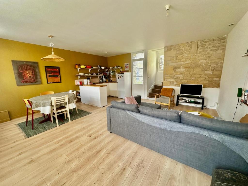 un salon avec un canapé et une salle à manger dans l'établissement La courette, maison avec cour proche plage, à Graye-sur-Mer