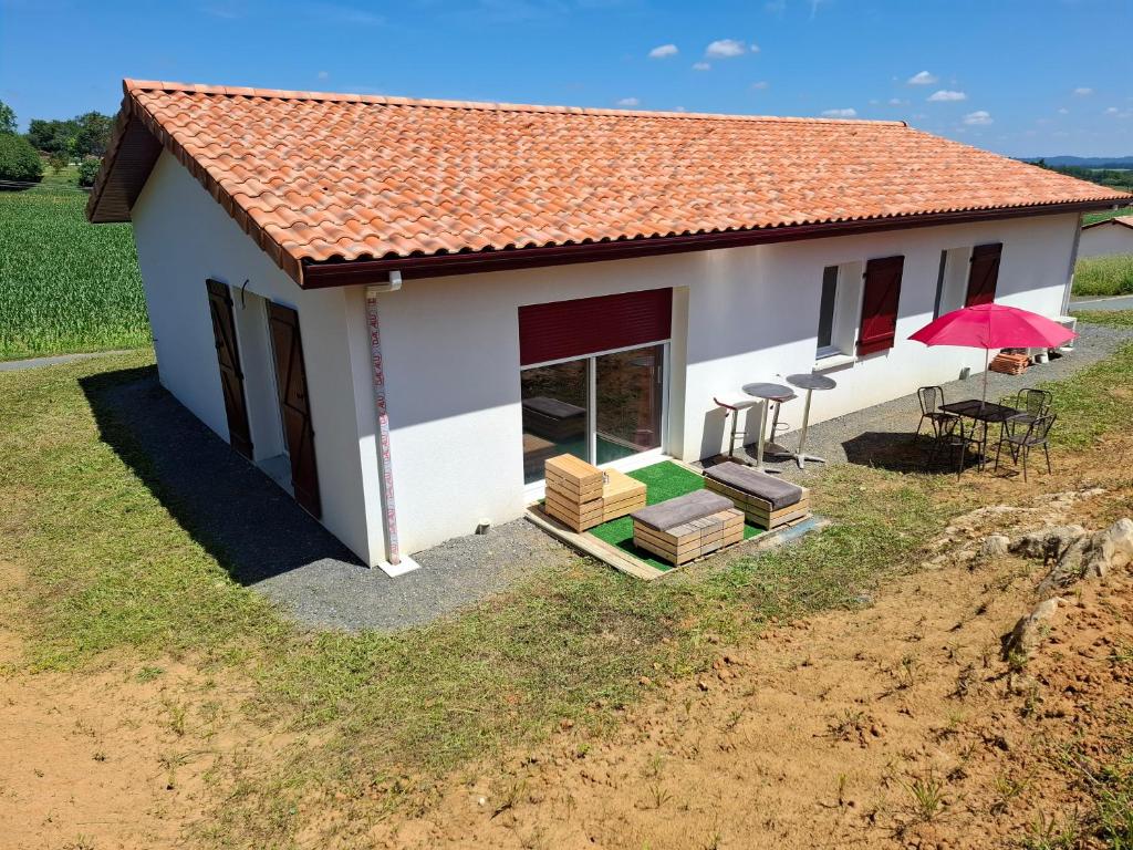 une petite maison blanche avec un toit rouge et des chaises dans l'établissement Maison de vacances avec jardin au Pays-Basque 88 m2, à Guiche