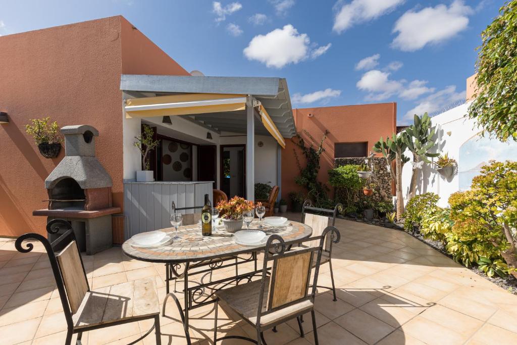 a patio with a table and chairs in front of a house at Home2Book Casa Kiky - Cosy Villa with Jacuzzi in La Oliva