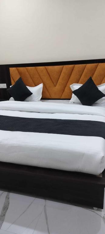 uma cama com almofadas pretas e brancas em Hotel Nandan - 800 Metres Away From Ram Mandir Ayodhaya em Ayodhya