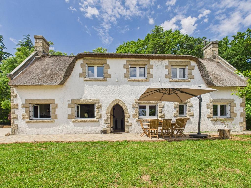an old stone house with a table and an umbrella at -TY TAD - Magnifique Chaumiere entierement renovee in Névez