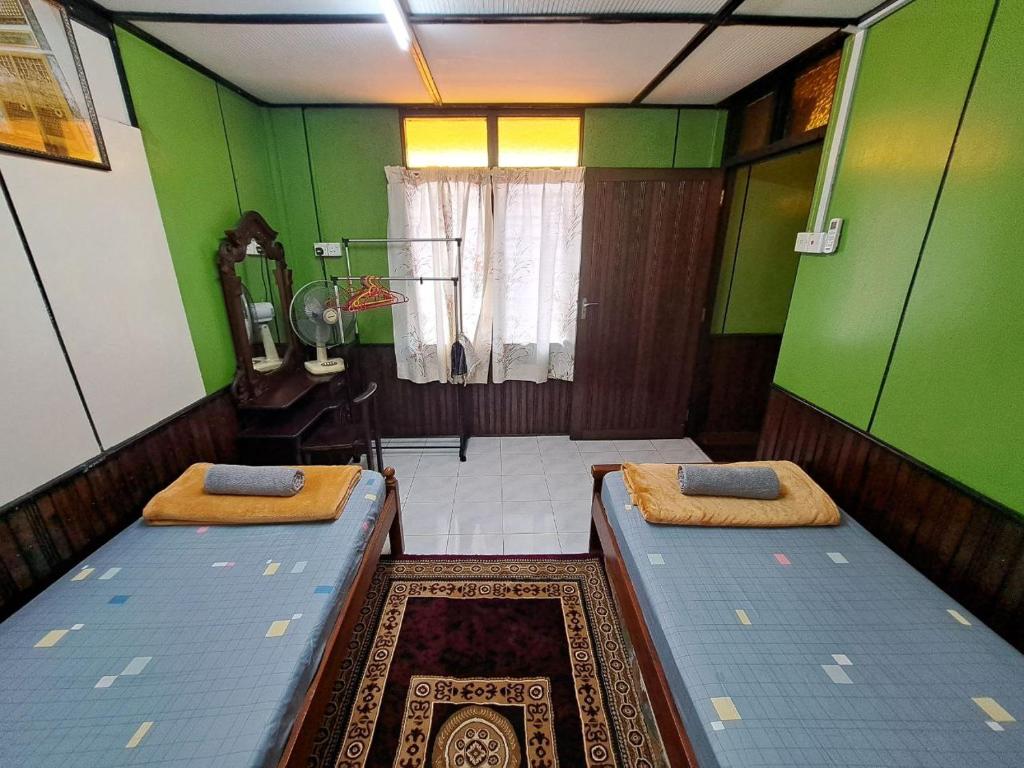 two beds in a room with green walls at Anggerik Homestay Kota Bharu in Kota Bharu