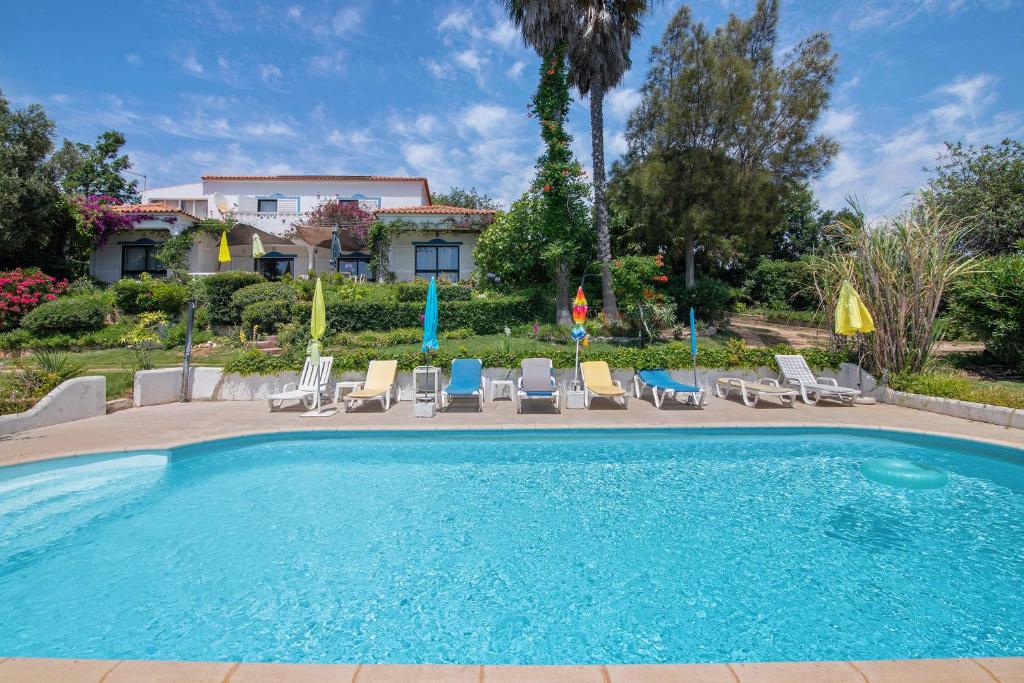 een zwembad met stoelen en een huis op de achtergrond bij Villa La Ribeyre in Boliqueime