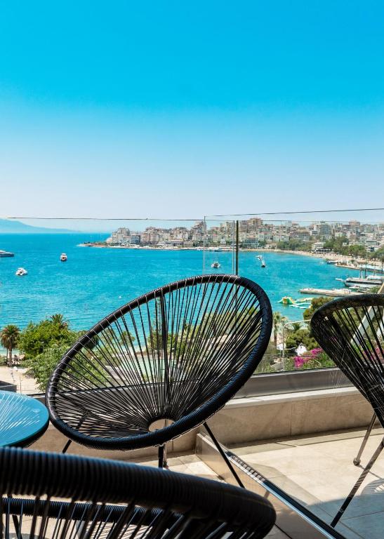 a bench sitting on a balcony with a view of the ocean at Kanes Boutique Hotel in Sarandë