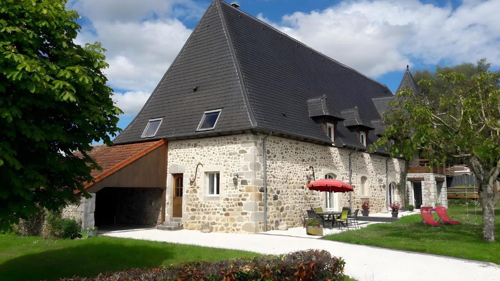 un grande edificio in pietra con tetto nero di Gite le Marronnier a Saint-Mamet-la-Salvetat