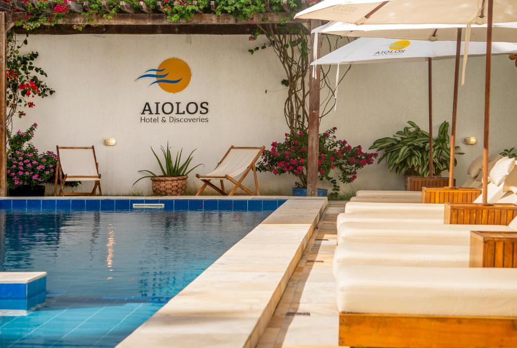 a pool with chairs and umbrellas next to a building at Aiolos Hotel & Discoveries in Prea