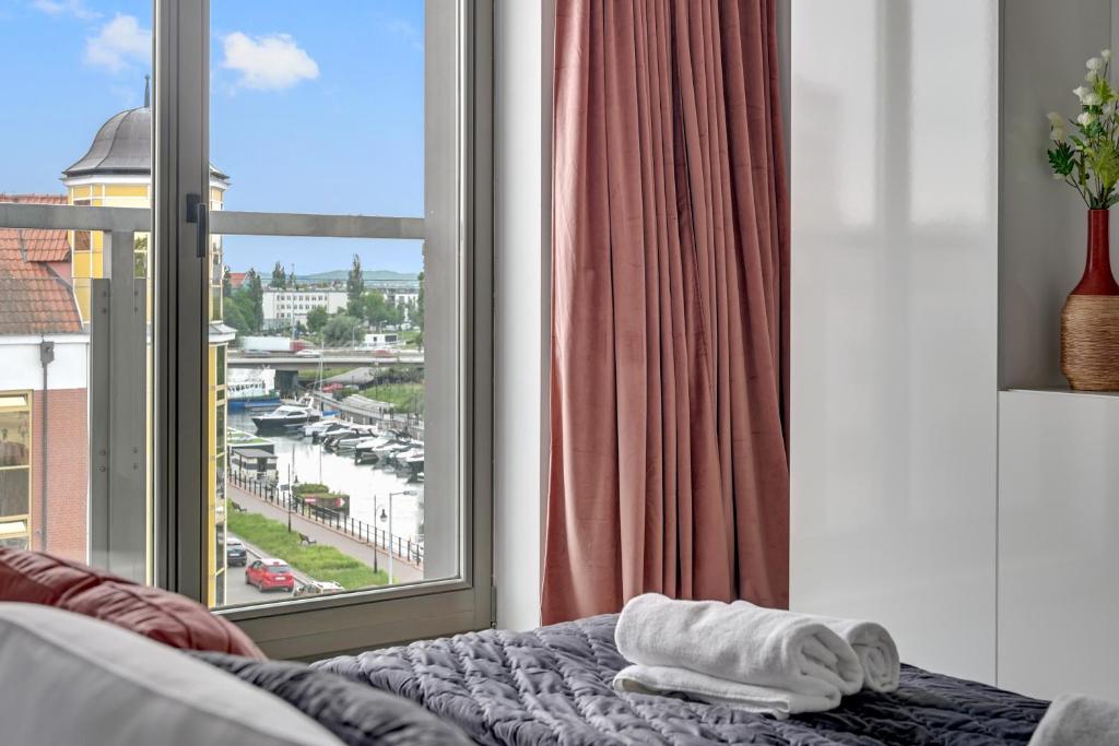 ein Schlafzimmer mit einem Fenster und ein Bett mit Handtüchern in der Unterkunft Waterlane Riverside - SPA, Pool, Gym &amp; Parking by Downtown Apartments in Danzig