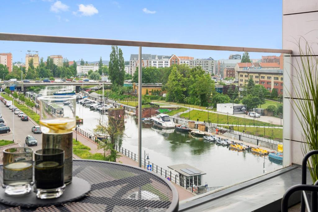 Blick auf einen Fluss von einem Tisch mit einem Getränk in der Unterkunft Waterlane Riverside - SPA, Pool, Gym &amp; Parking by Downtown Apartments in Danzig