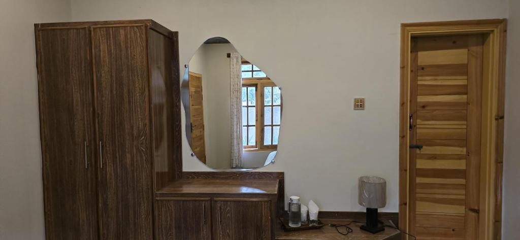 a bathroom with a wooden cabinet and a mirror at Rosho Skardu in Skardu
