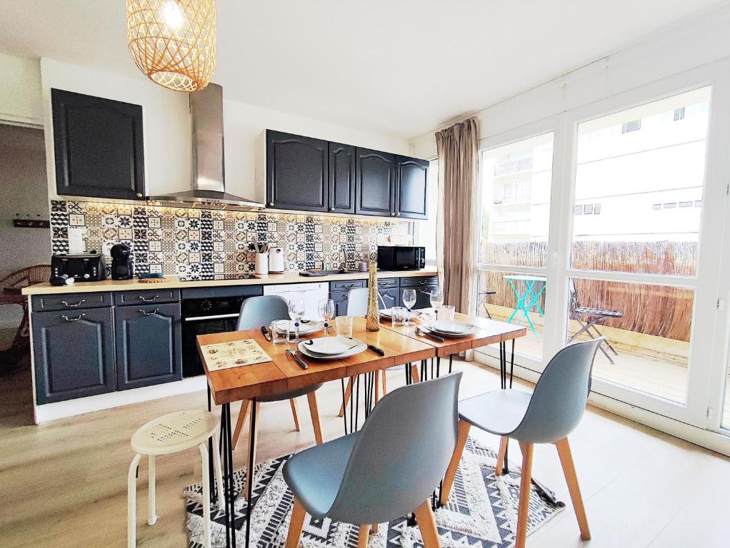 une cuisine avec une table et des chaises en bois ainsi qu'une grande fenêtre dans l'établissement Appartement 4 chambres - CAEN, à Caen