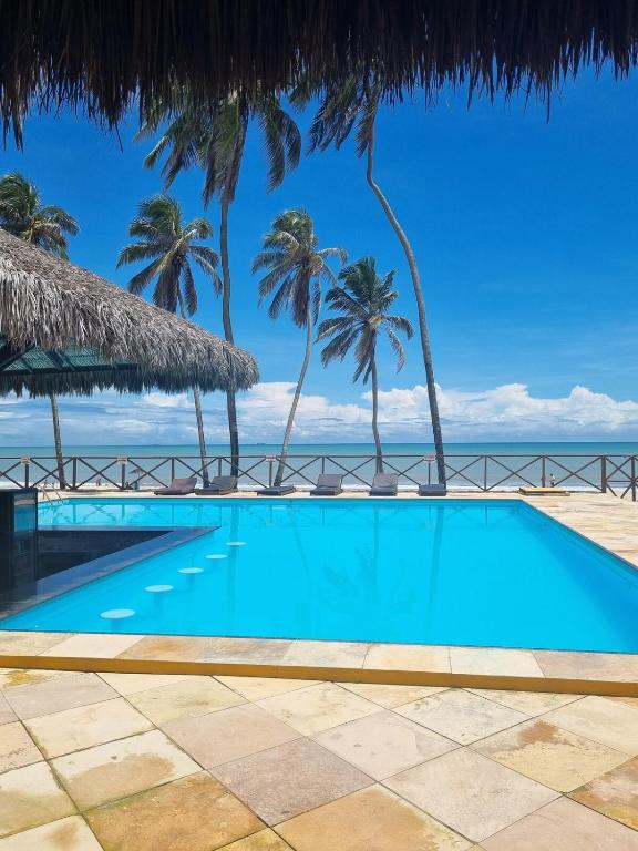 a swimming pool with palm trees and the ocean at Ecoparadise Flat 103 in Caucaia