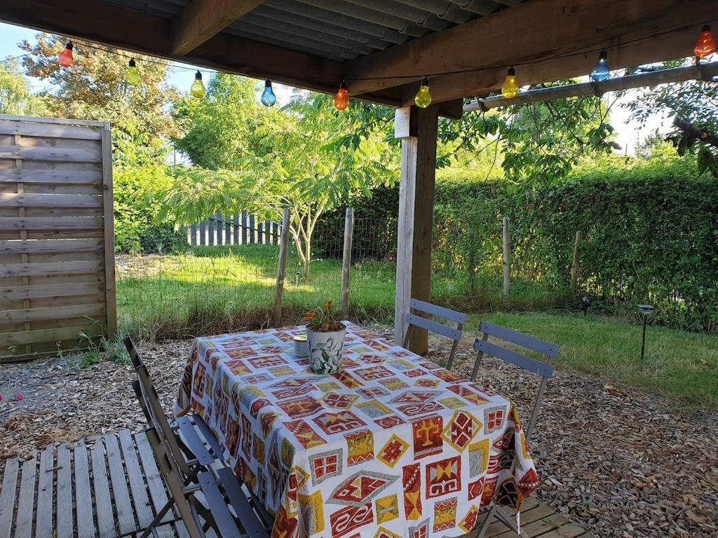 a table with a table cloth sitting under a pergola at Petite maison proche Marais Poitevin, Puy dufou in La Ronde