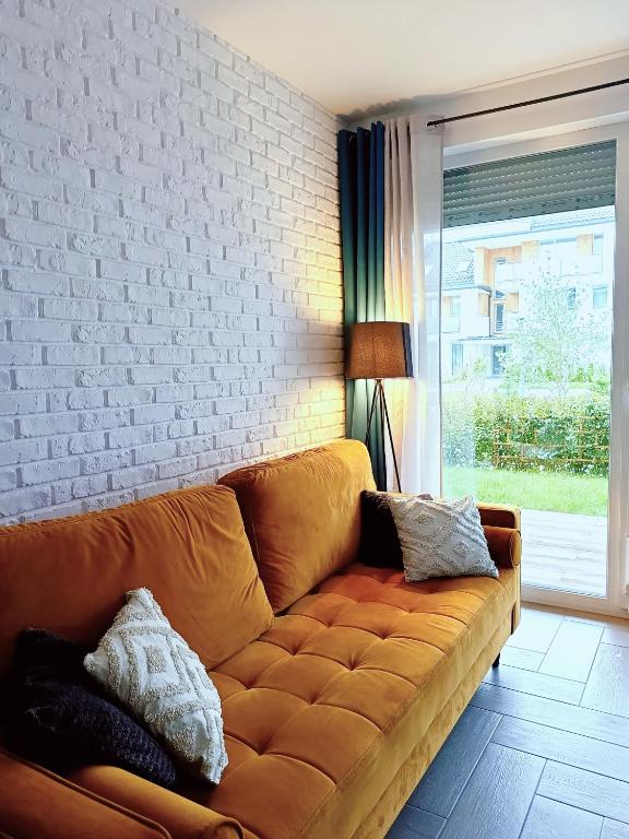 a couch in a living room with a brick wall at Apartament Sand&Blue z basenem in Sztutowo