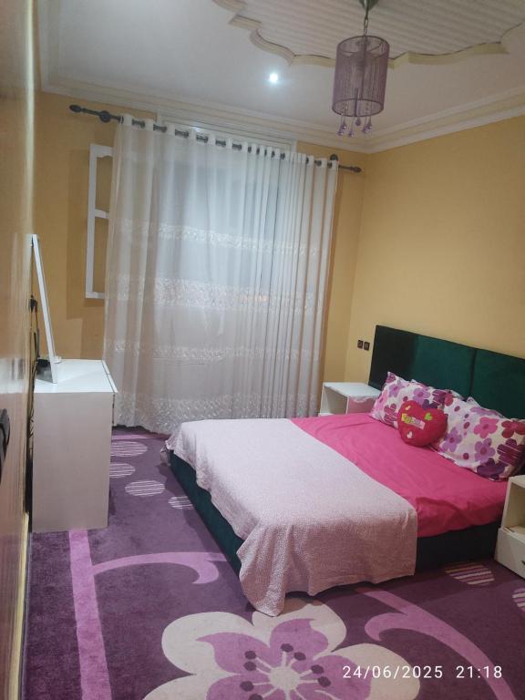 a bedroom with a bed with pink sheets and a purple carpet at Mogadorista pour les familles in Essaouira