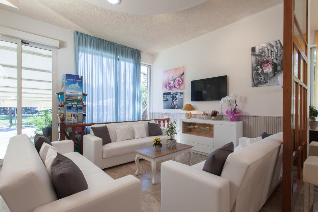a living room with white furniture and a tv at Hotel Olympic in Milano Marittima