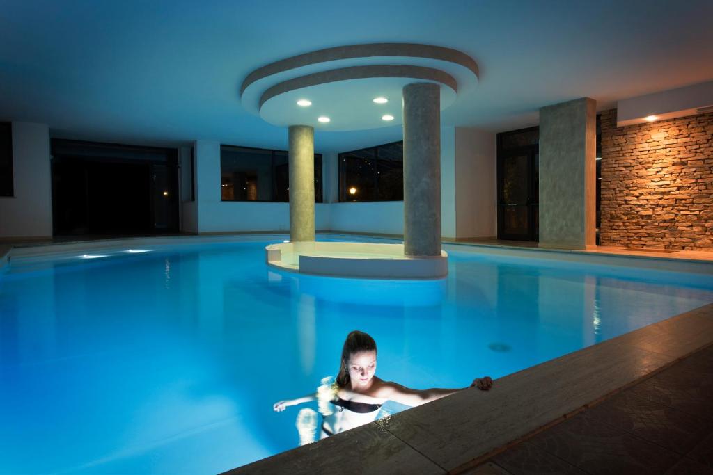 a woman laying in a swimming pool at a hotel at Albergo Ristorante San Biagio in Montepulciano