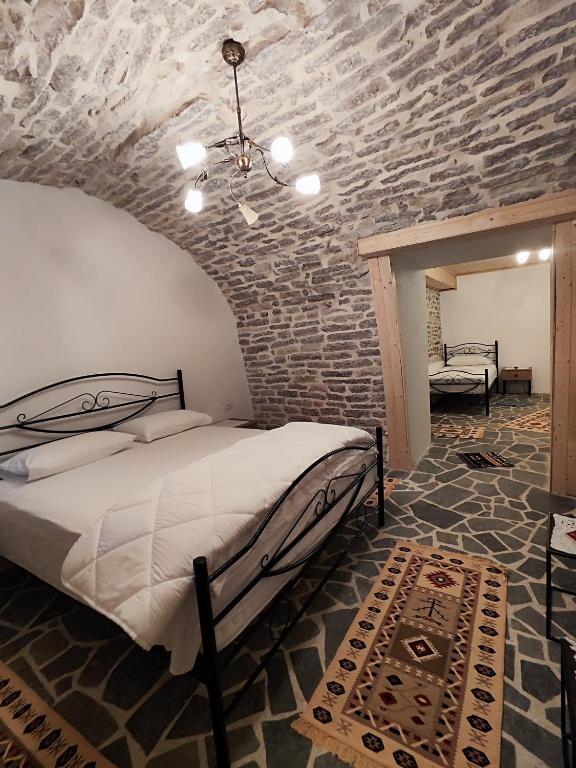 a bedroom with a bed and a stone wall at Guri Guesthouse in Gjirokastër