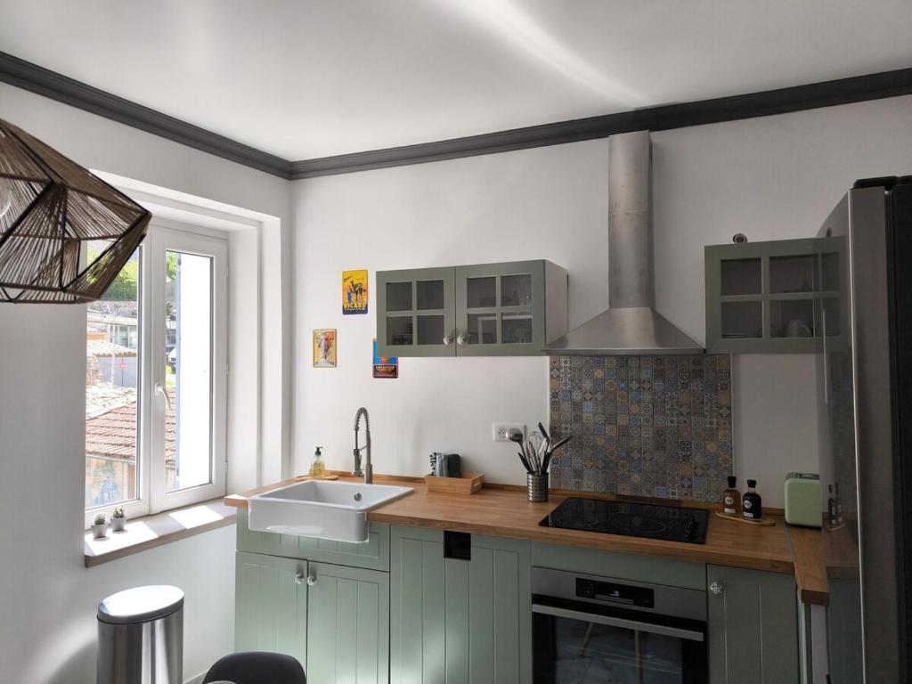 a kitchen with green cabinets and a sink and a window at Maison au coeur de Banon in Banon