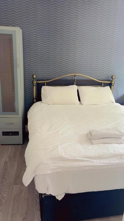 a bed with white sheets and pillows in a room at Jacuzzi City Guesthouse, about a 7 min walk to Racecourse and 10 mins to the City in Doncaster