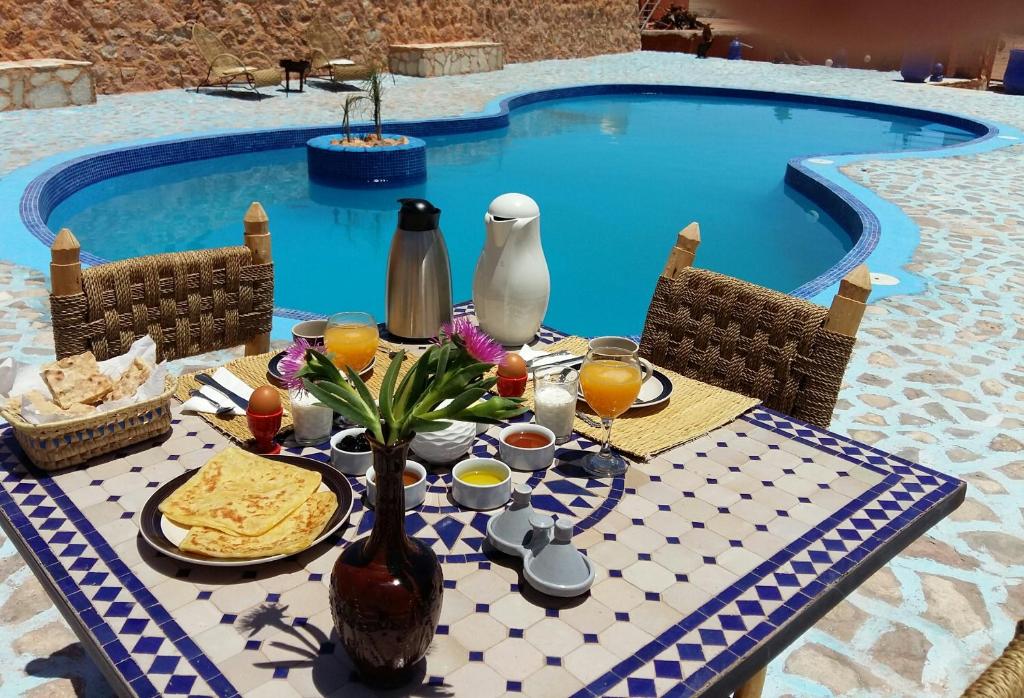 uma mesa com comida e bebidas junto a uma piscina em Riad Paradise of Silence em Aït Ben Haddou