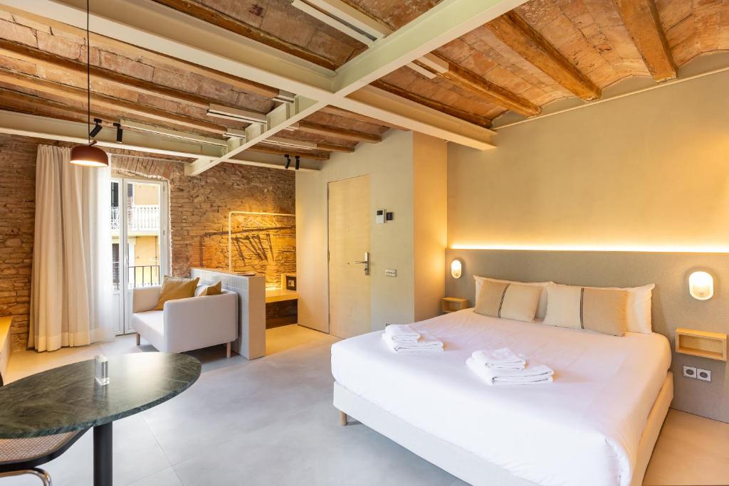 a bedroom with a large white bed and a table at Decô Apartments Barcelona-Born St. in Barcelona