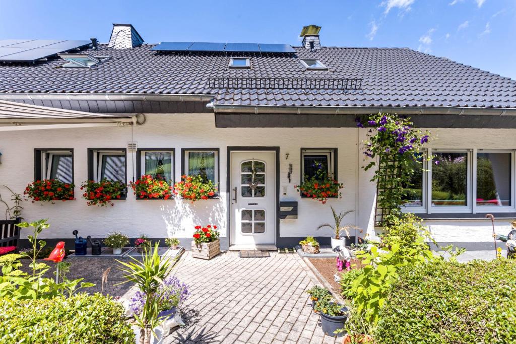 ein weißes Haus mit Blumen im Vorgarten in der Unterkunft Ferienwohnung Am Waldrand in Schmallenberg