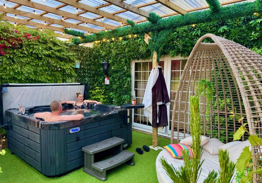 two people in a hot tub in a garden at FINN VILLAGE - Loch Lomond Villa - THE JUNGLE ROOM with a PRIVATE HOT TUB in Drymen