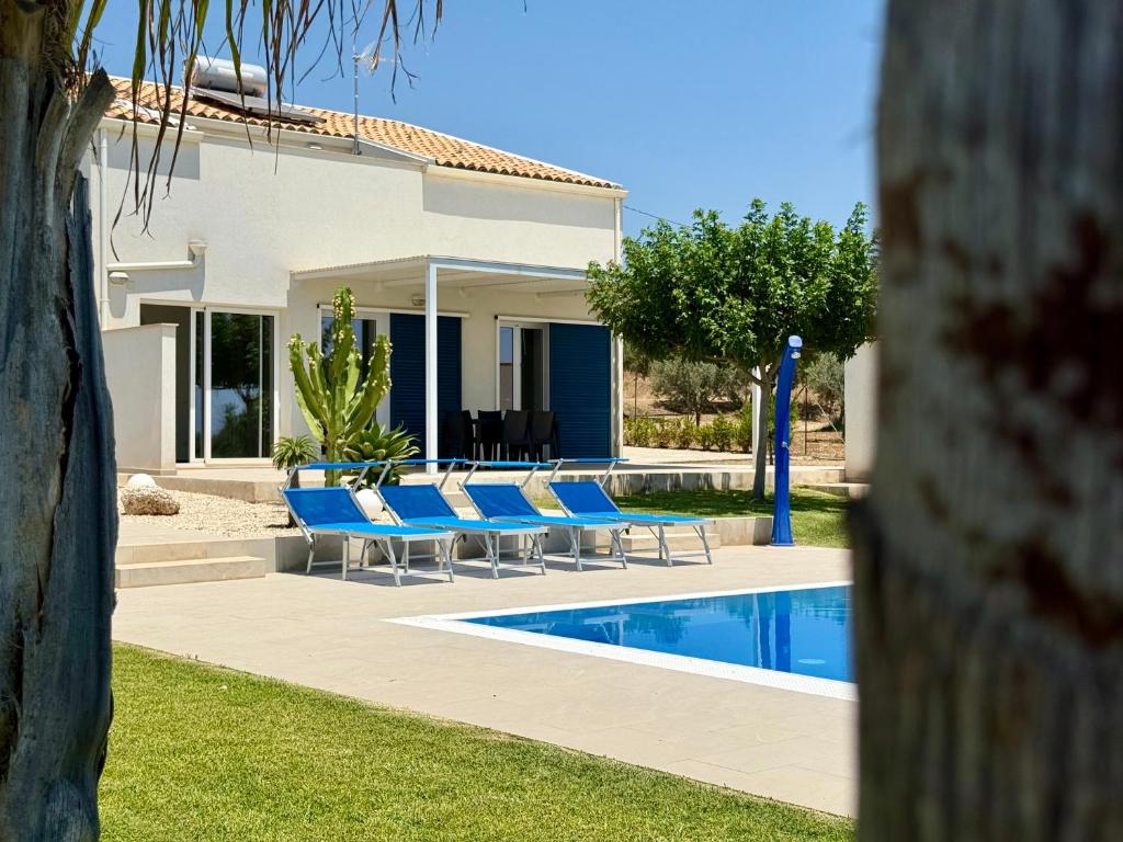 une villa avec une piscine et des chaises bleues dans l'établissement Villa Sema - Marina di Ragusa, à Marina di Ragusa