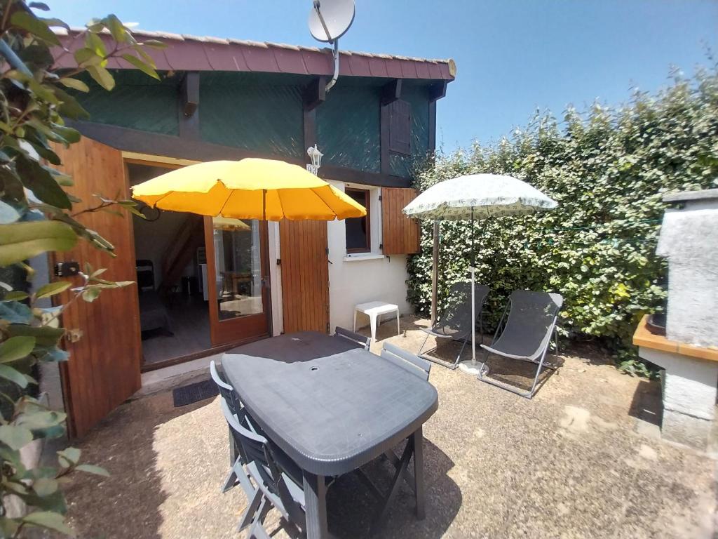 une table avec un parapluie jaune et deux chaises dans l'établissement Biscarrosse-plage jolie maisonnette avec terrasse privative - 200m de la plage, à Biscarrosse