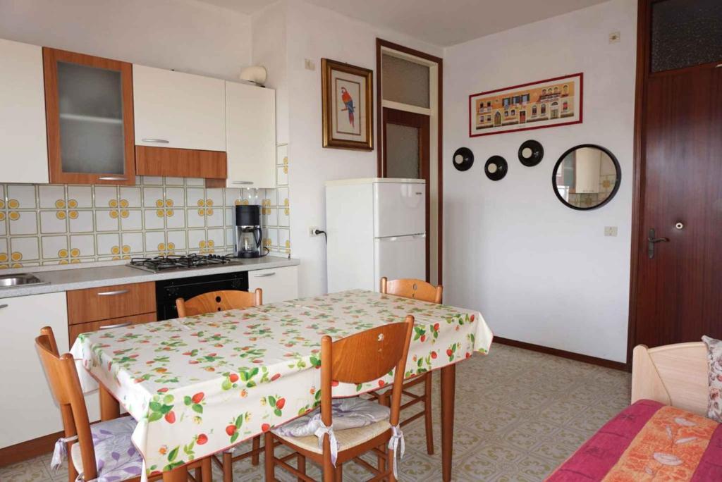 kuchnia ze stołem i białą lodówką w obiekcie Apartment in Porto Santa Margherita 42874 w mieście Porto Santa Margherita di Caorle