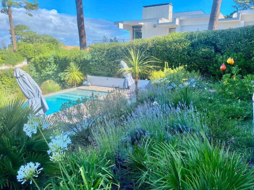 un jardin avec une piscine et des fleurs dans l'établissement Appartement vue mer piscine, à La Teste-de-Buch