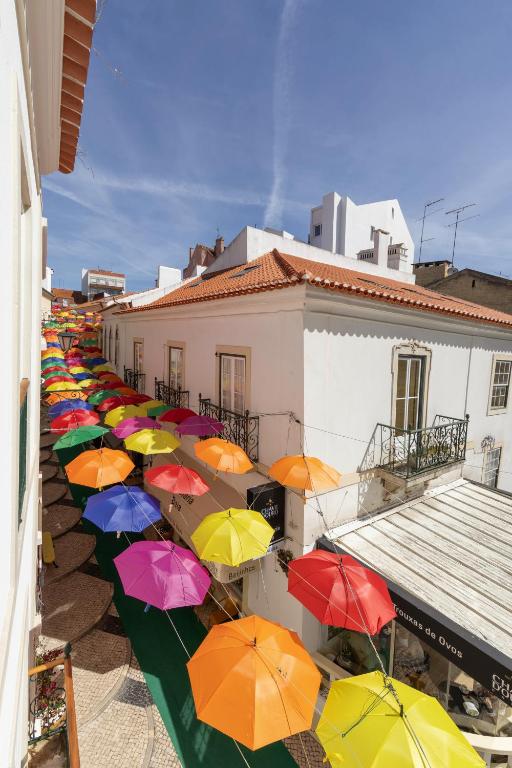 a row of colorful umbrellas in front of buildings at Solar das Termas in Caldas da Rainha