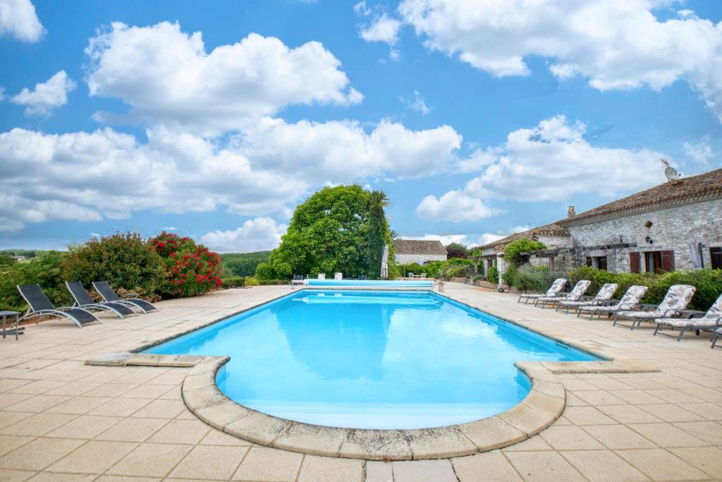 une grande piscine avec des chaises et une maison dans l'établissement Le Nid, à Razac-dʼEymet