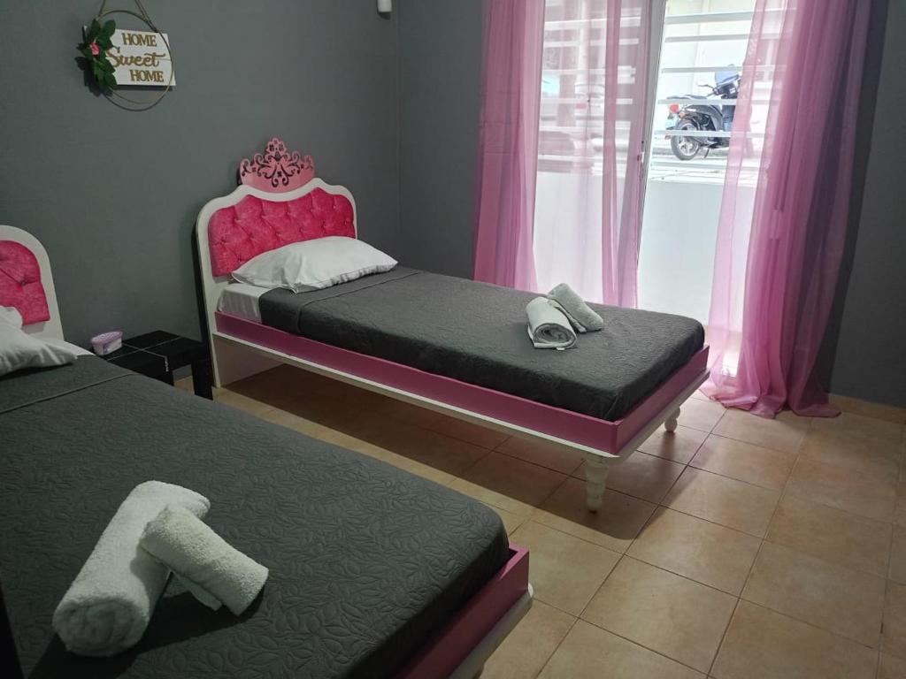 twee bedden in een kamer met roze gordijnen en roze bedden bij Alexandroupolis City Home Eftelya 50m City Best Location in Alexandroupoli