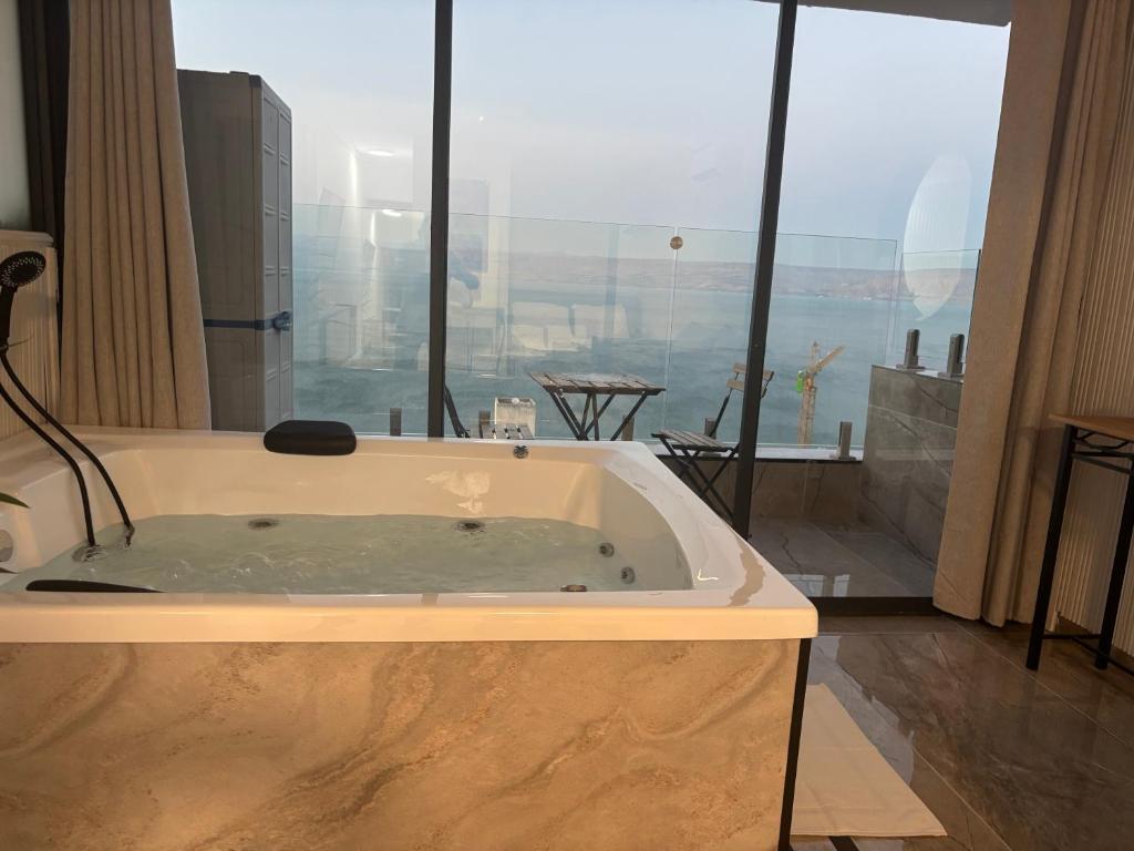 a bath tub in a room with a large window at פרמיום בכינרת in Tiberias