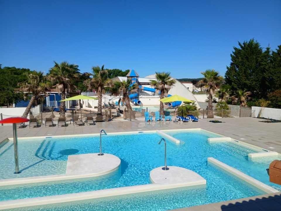 une piscine dans un complexe hôtelier avec chaises et parasols dans l'établissement Les Chalets de Moulière, à Vouneuil-sur-Vienne