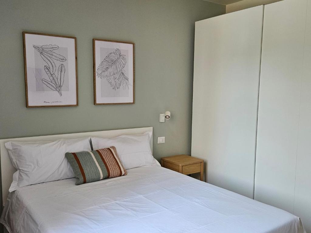 a bedroom with a white bed with two framed drawings on the wall at LuMI Apartment in Basiglio