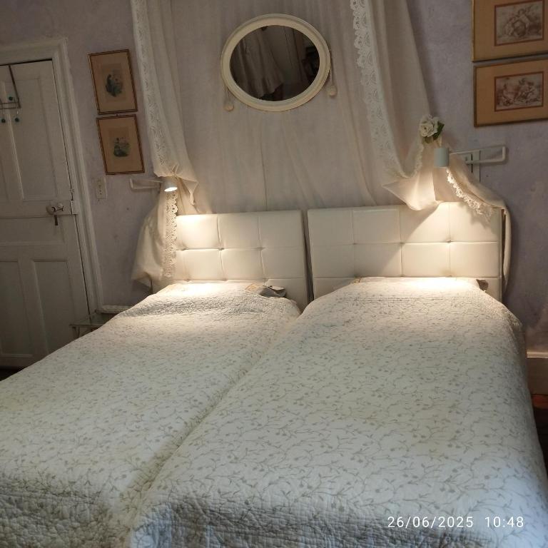 une chambre avec deux lits et un miroir dans l'établissement Grand appartement de charme avec parking privé, à Florac